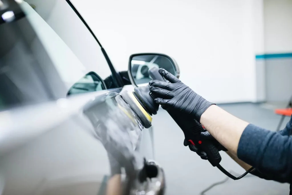 Car polishing image showing a technician buffing the exterior of a vehicle to achieve a mirror-like shine